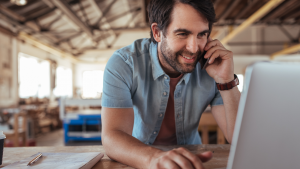 Self-employed woodworker talking on phone whilst using laptop