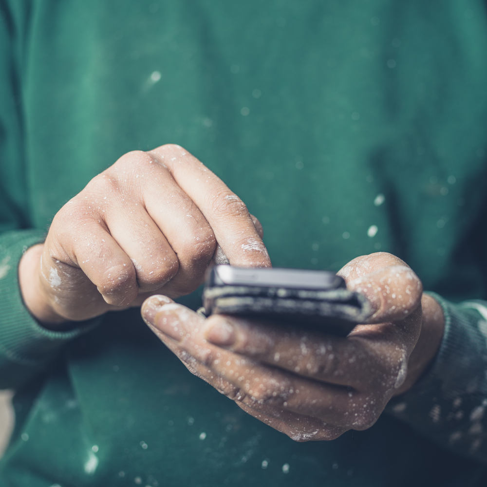 Man in green jumper holding a smartphone
